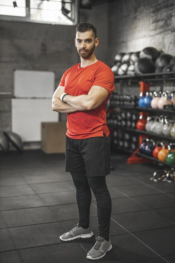 a man standing in a gym with his arms crossed