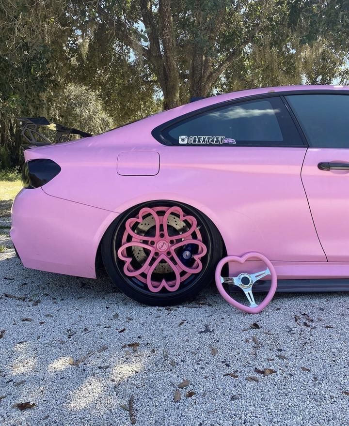 the pink car is parked on the side of the road with its wheels in front of it