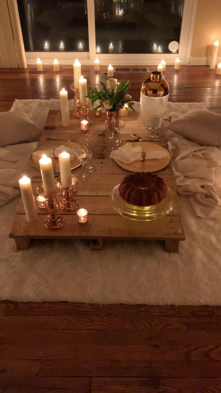 a table with candles and cake on it in the middle of a room filled with blankets