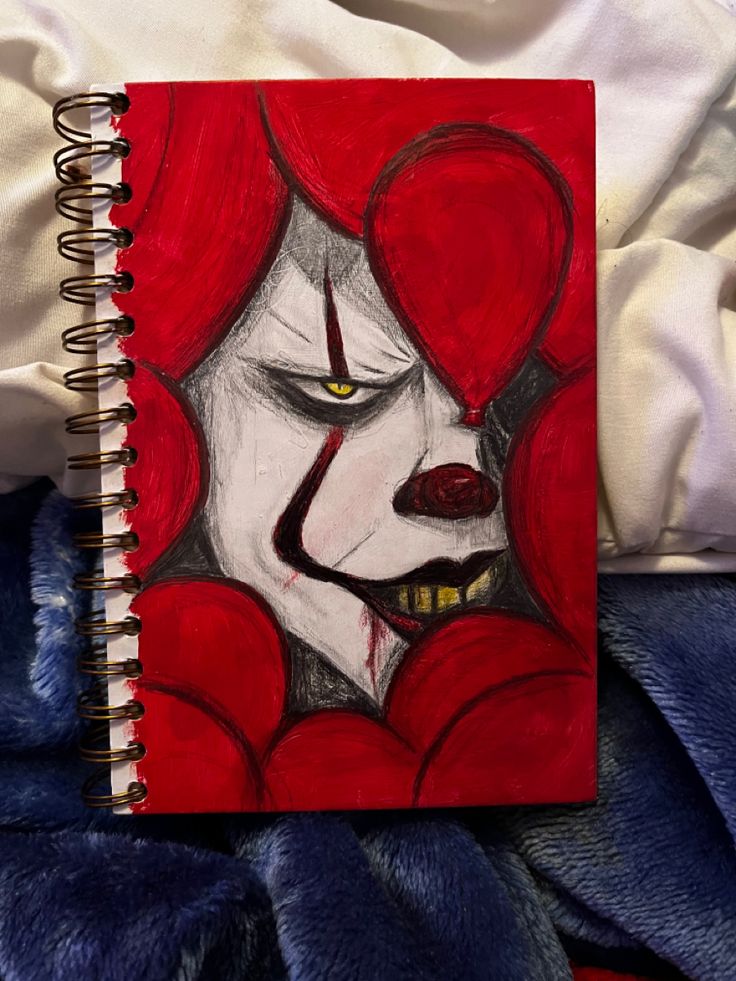 a drawing of a clown with red hair and yellow eyes is on a blue blanket