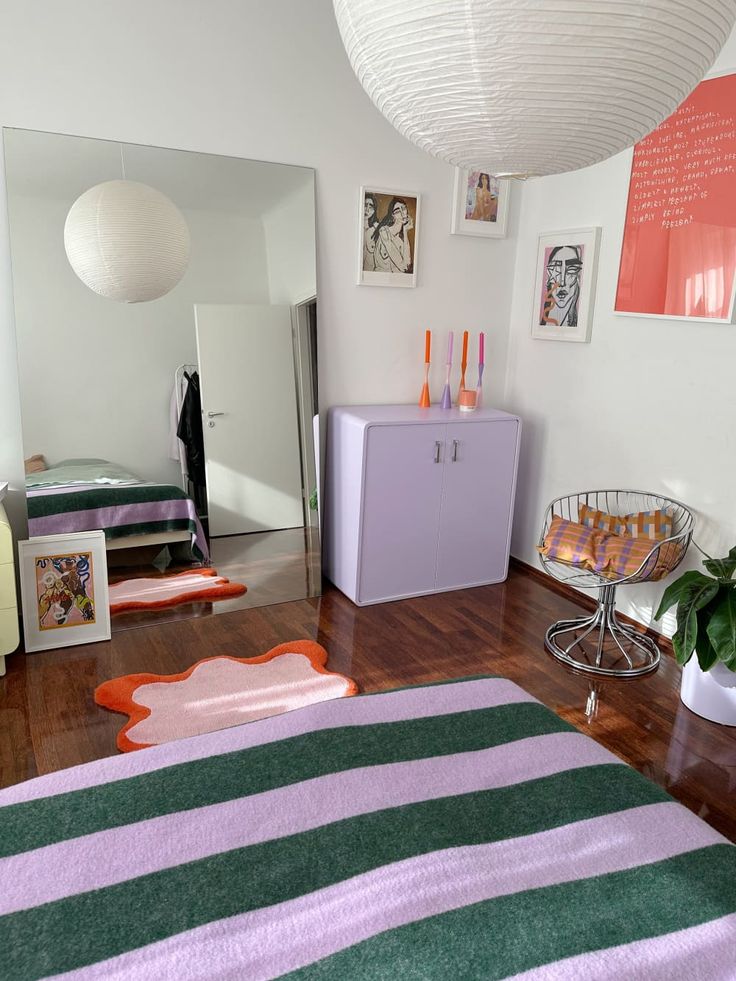 a room with a bed, dresser and rugs on the wooden floor in front of a mirror