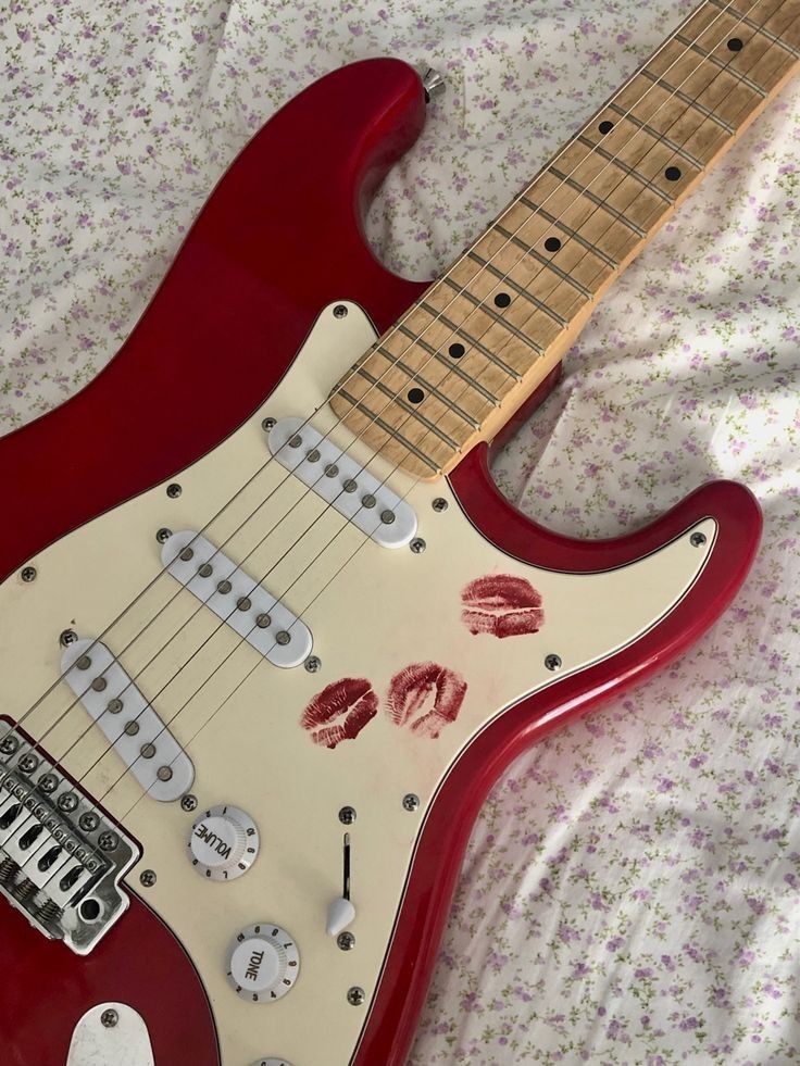 a red electric guitar sitting on top of a bed