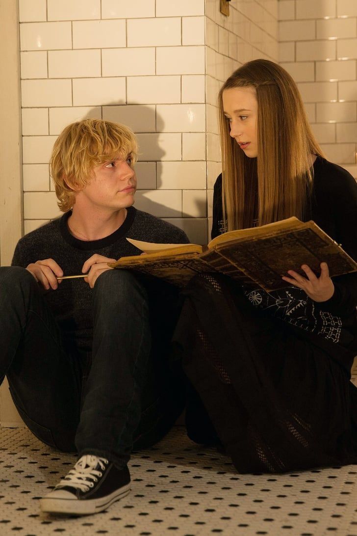 two people sitting on the floor reading a book