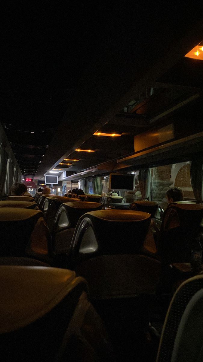 the interior of a bus at night with its lights on and people sitting in seats