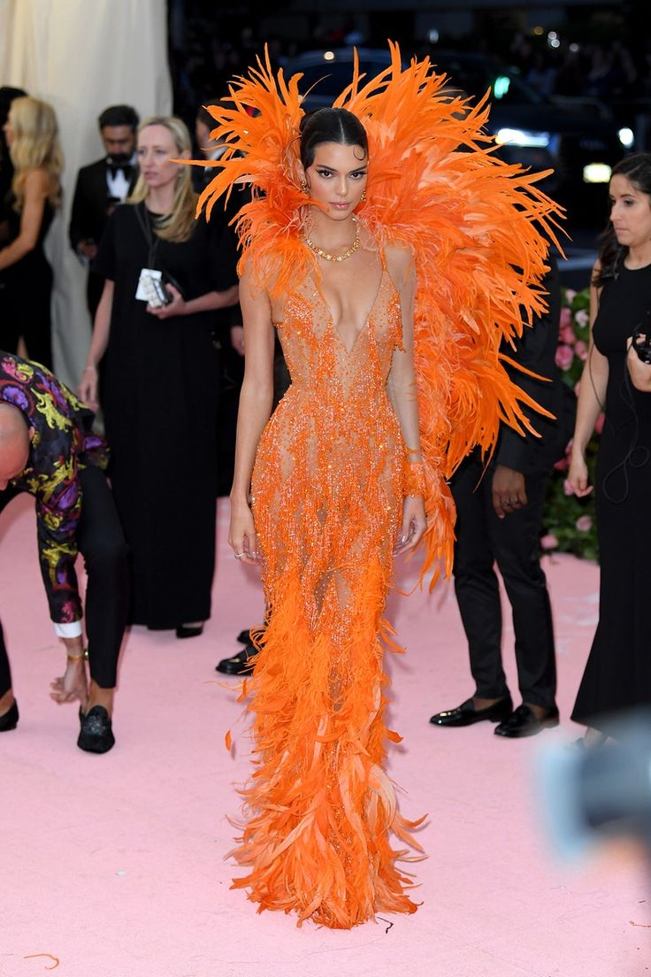 a model walks the runway in an orange feathered gown