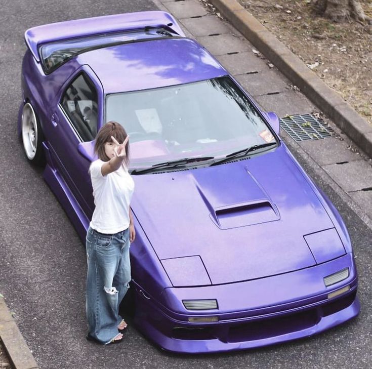 a woman leaning on the hood of a purple sports car