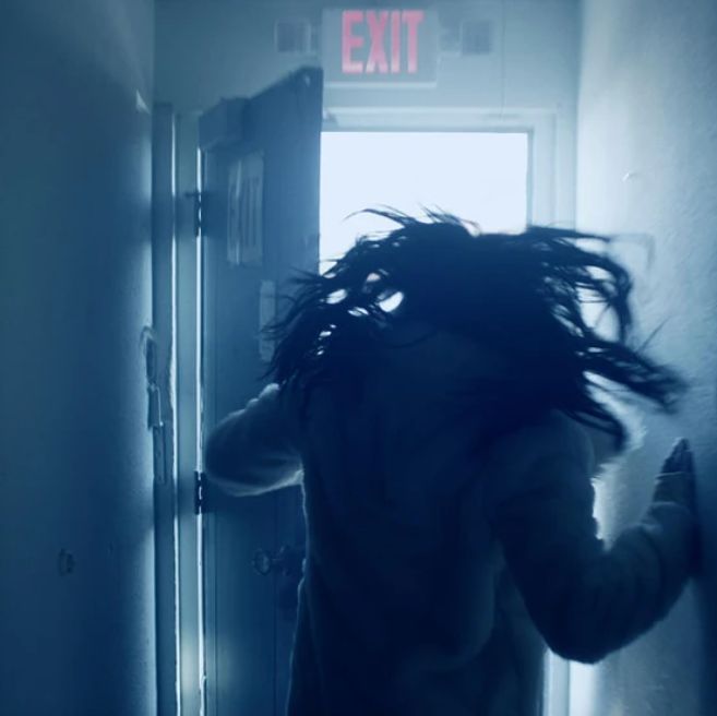 a person with long hair standing in front of a door