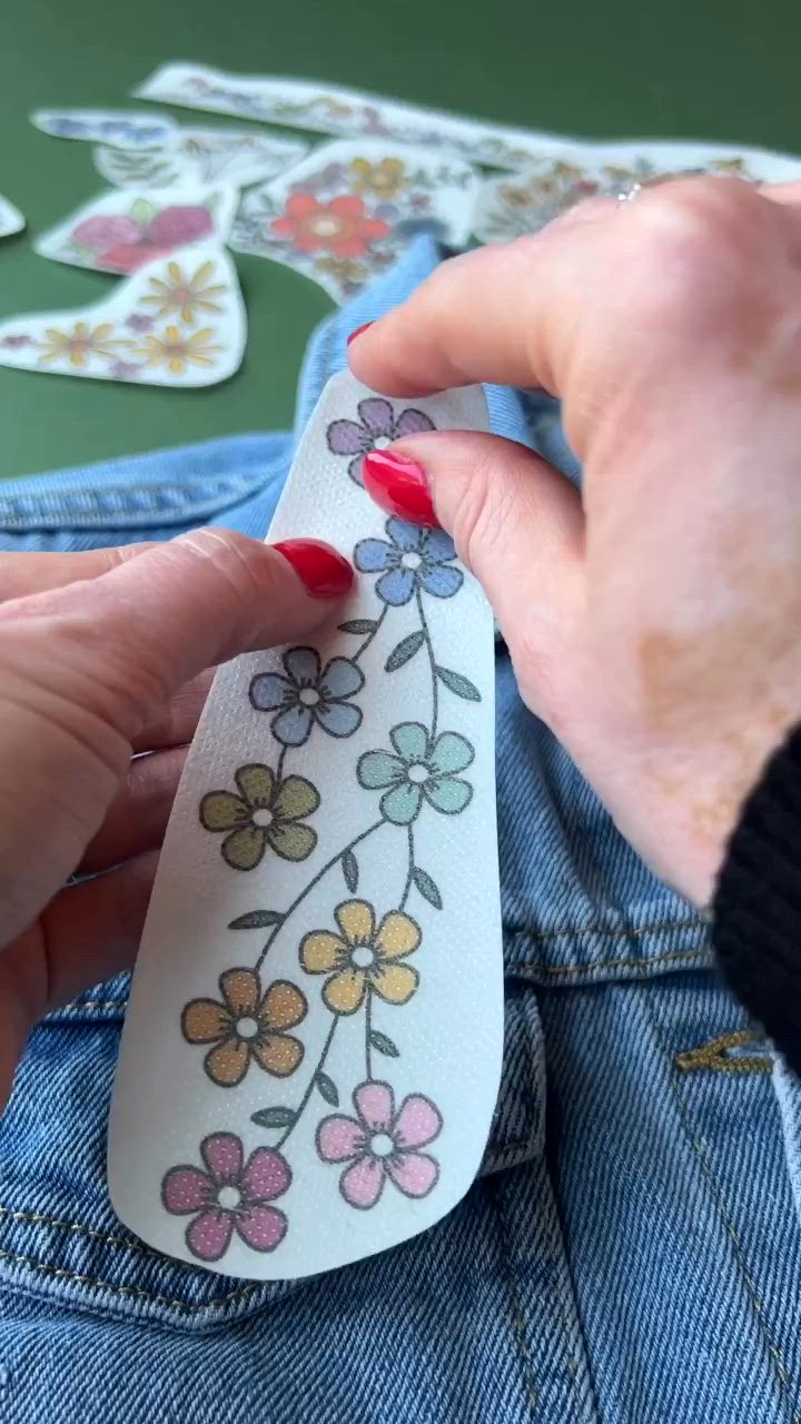 This may contain: someone is stitching flowers on the back of their jean jacket