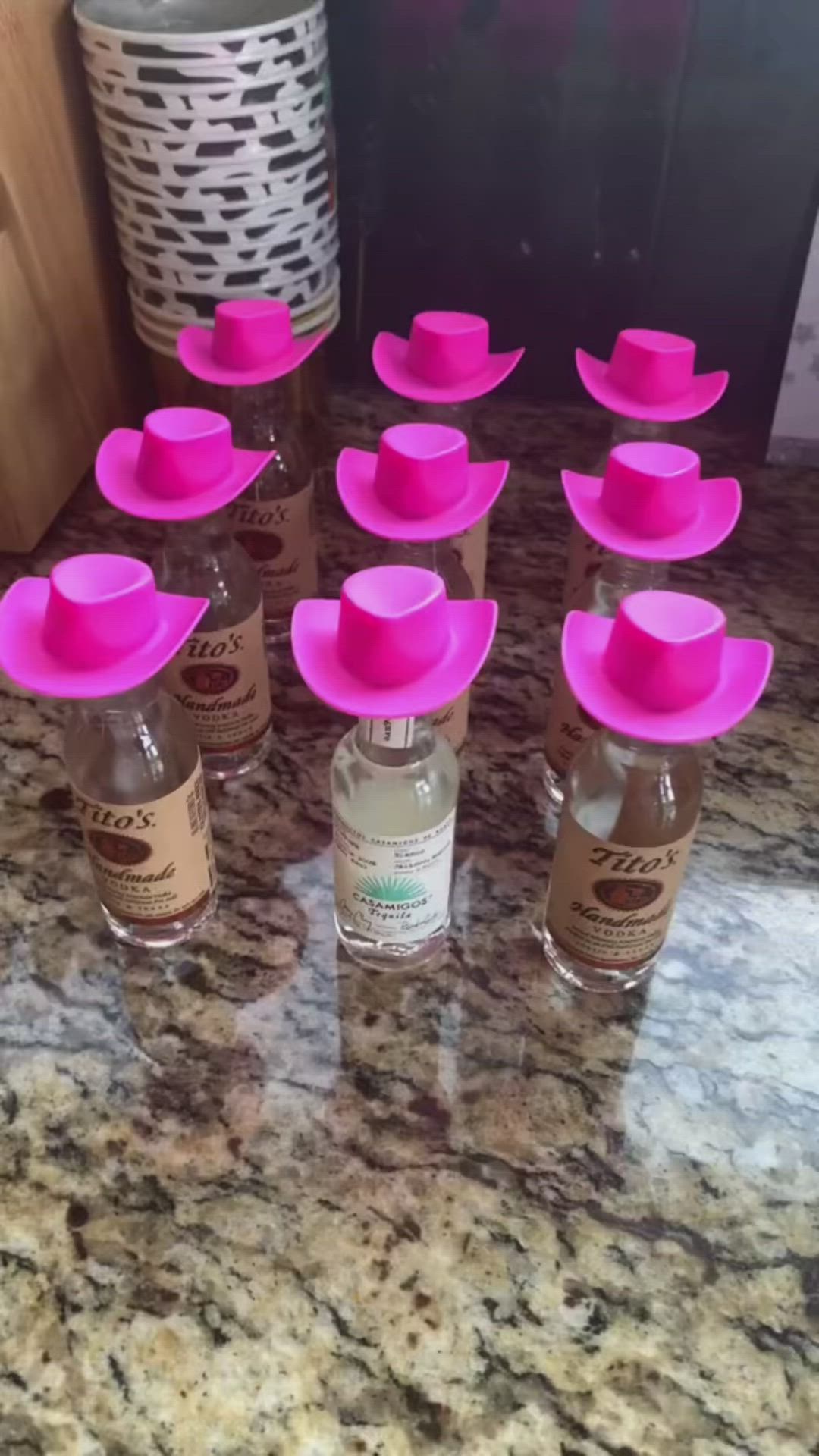This may contain: there are many bottles with pink hats on the top and one bottle is filled with water