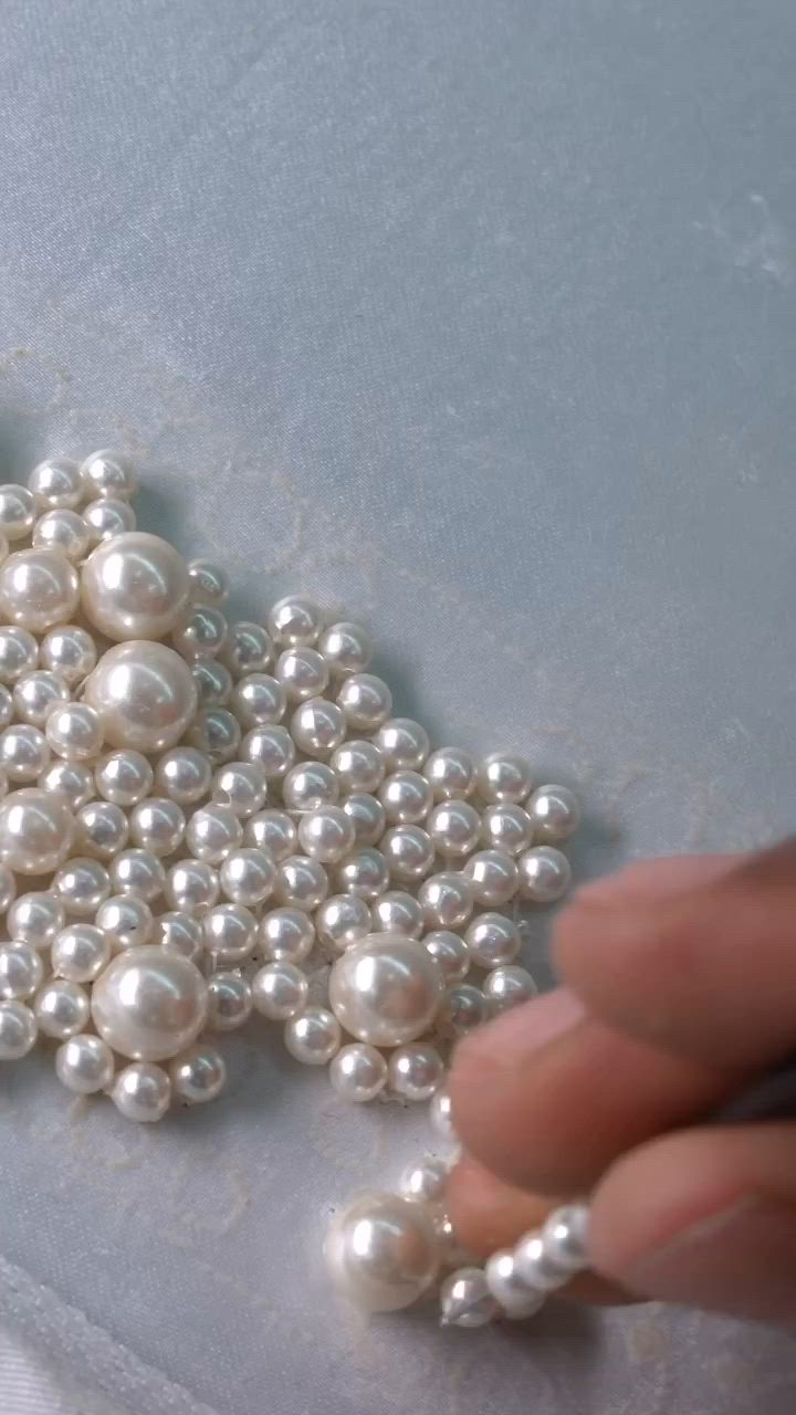 This may contain: a person is working on some white pearls