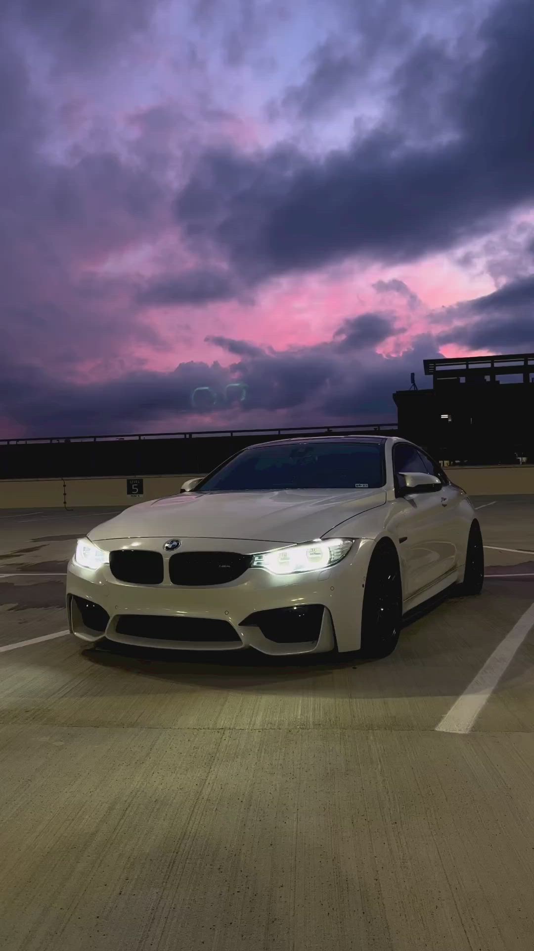 This may contain: a white car parked in a parking lot under a purple and blue sky with clouds