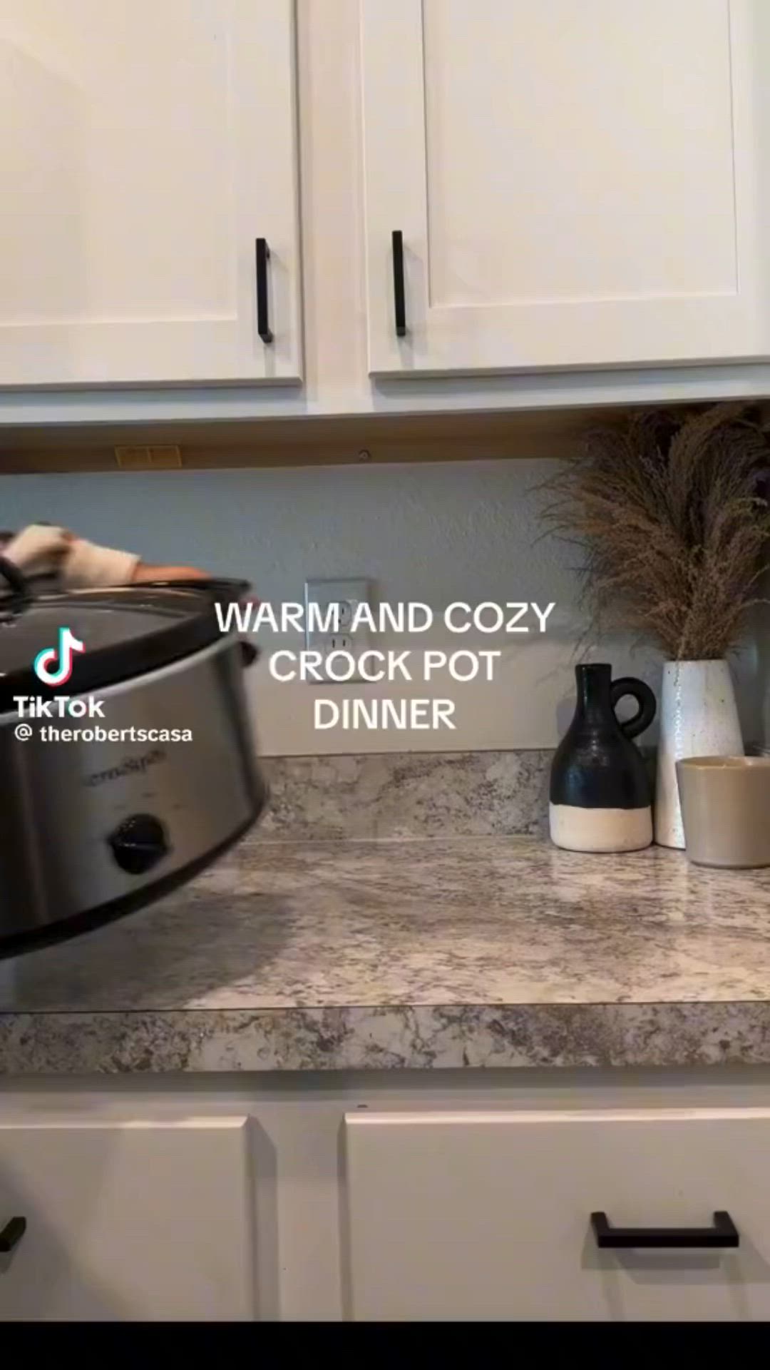 This may contain: a crock pot sitting on top of a kitchen counter next to white cupboards