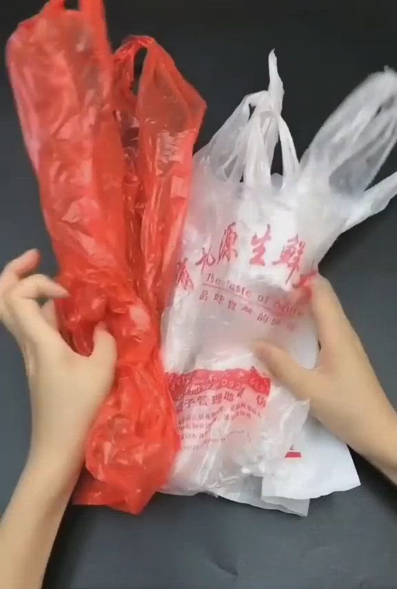 This may contain: two hands are holding plastic bags with chinese writing on them and one hand is reaching for the bag