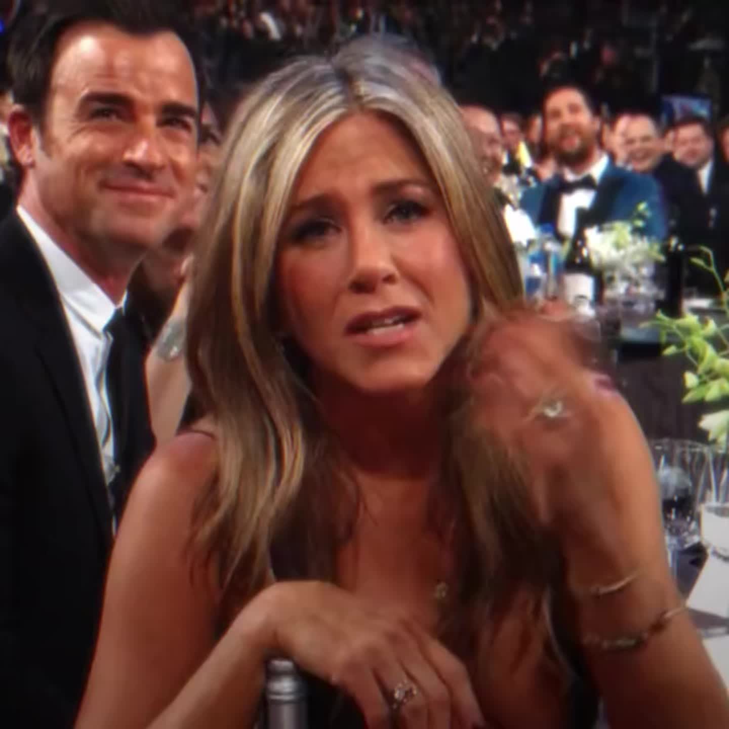 This may contain: an image of a woman sitting at a table in front of a man who is wearing a suit and tie