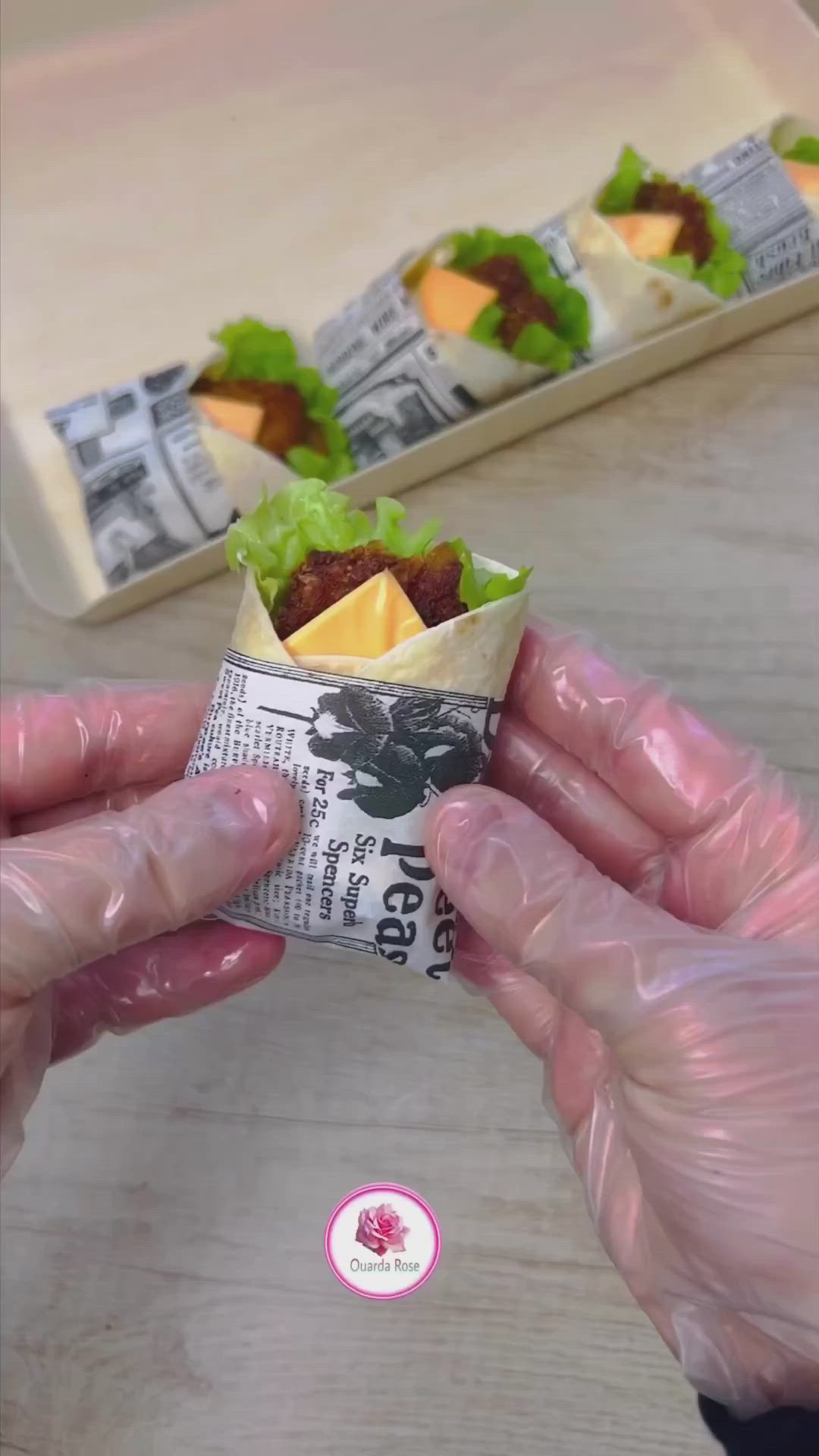 This may contain: two hands are holding food wrapped in plastic on a wooden table next to another person's hand