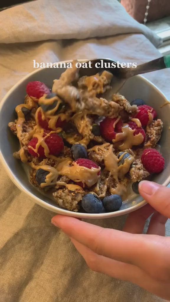 This may contain: a person is holding a bowl of cereal with berries and yogurt on top