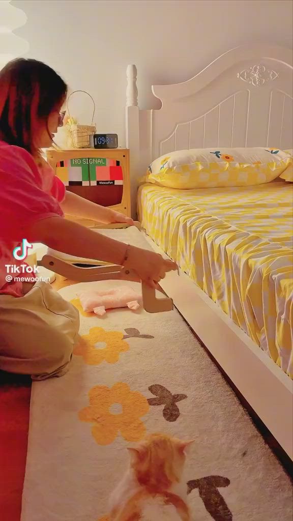 This may contain: a woman kneeling on the floor in front of a bed with yellow and white bedspread