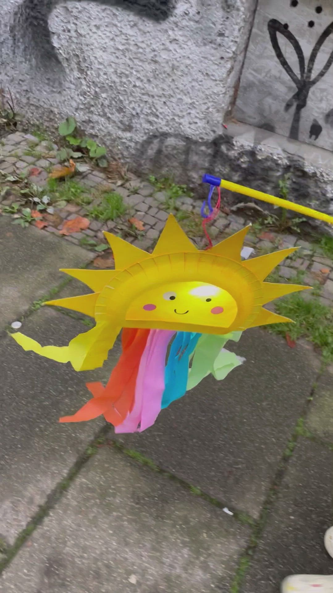 This may contain: a kite that is shaped like a sun and has a face on the top of it