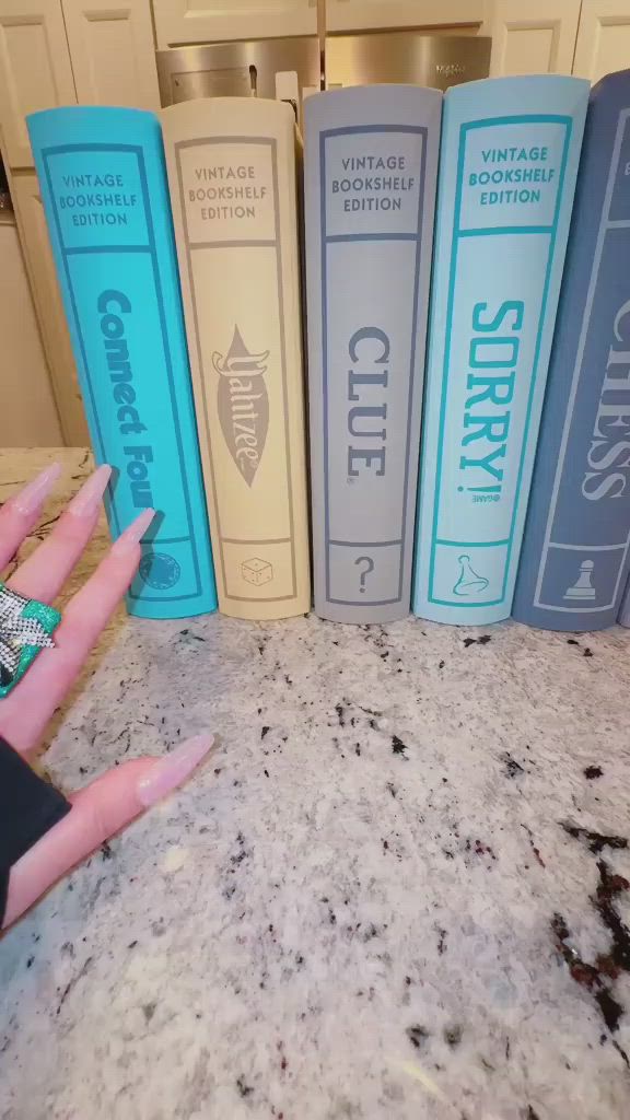 This may contain: a woman's hand is shown in front of three blue and yellow book cases