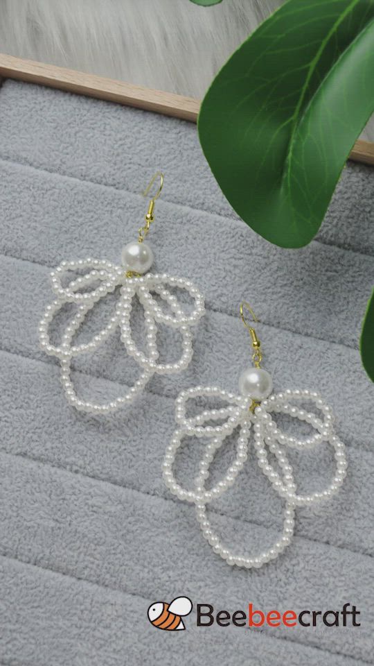 This may contain: the earrings are made with pearls and gold plated hooks, on a gray surface