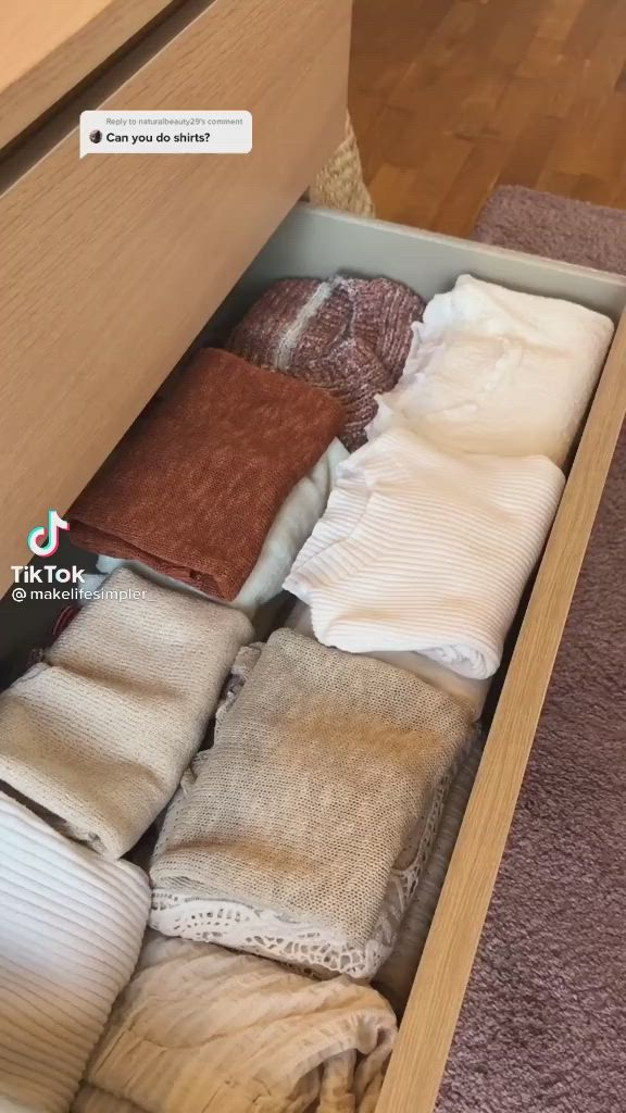 This may contain: an open drawer filled with lots of sweaters on top of carpeted flooring