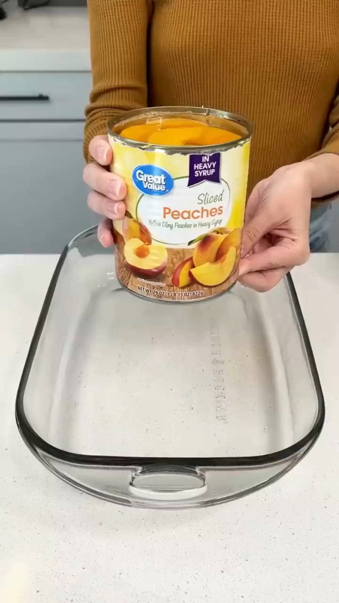 This may contain: a woman holding up a bowl of peaches on top of a kitchen countertop