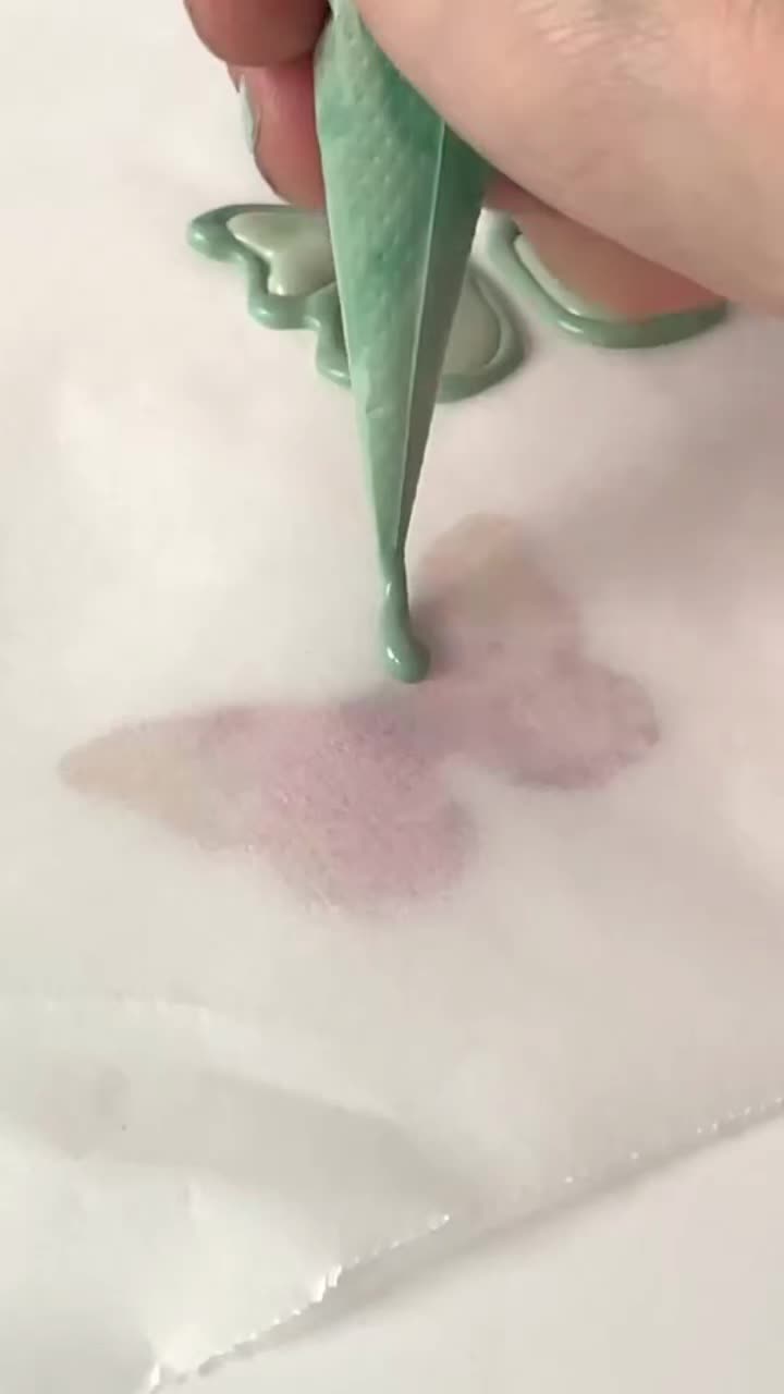 This may contain: a person is using a green plastic object to paint the surface with pink and white colors