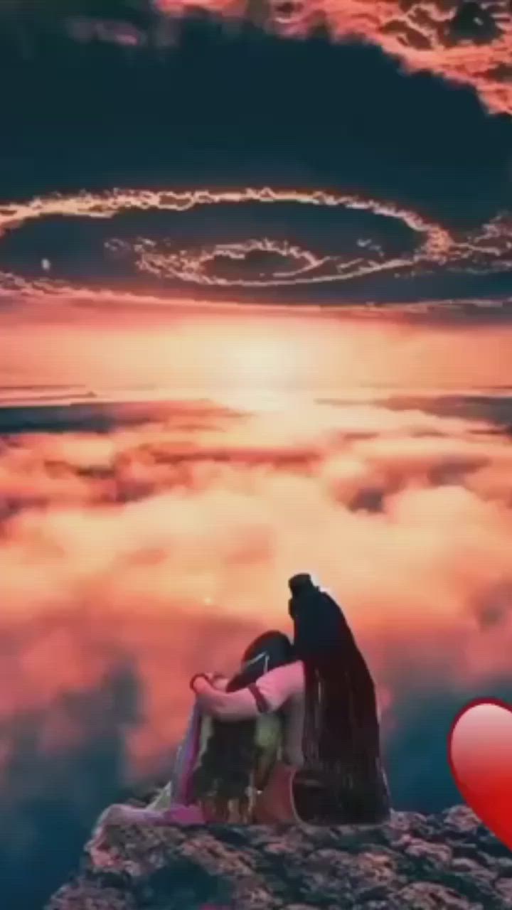 This may contain: a woman sitting on top of a rock next to a red heart in the sky