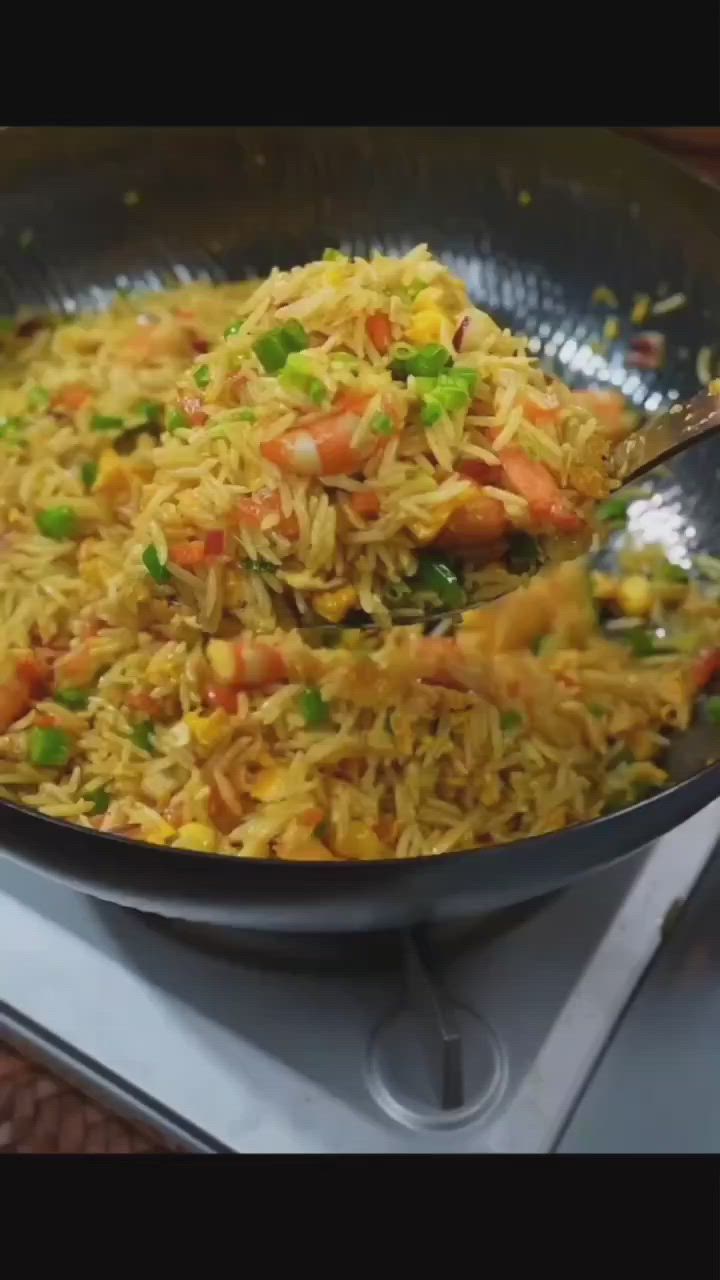 This may contain: a pan filled with rice and vegetables on top of a stove