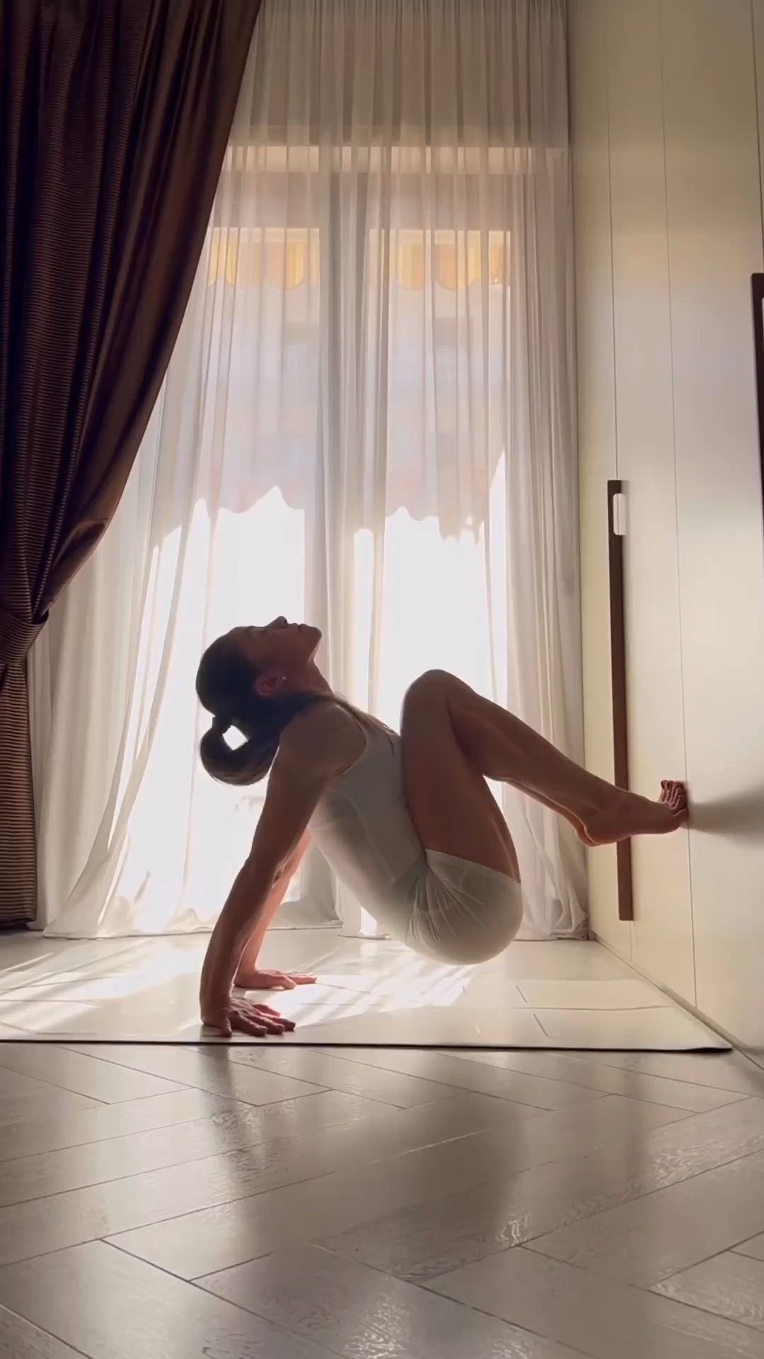 This may contain: a woman is doing yoga on the floor in front of a window with sheer curtains