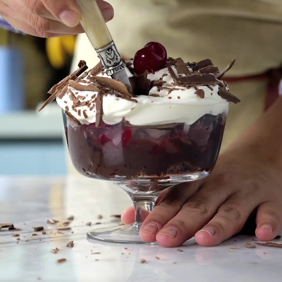 This may contain: a dessert with chocolate and cherries in a small glass dish on a counter top