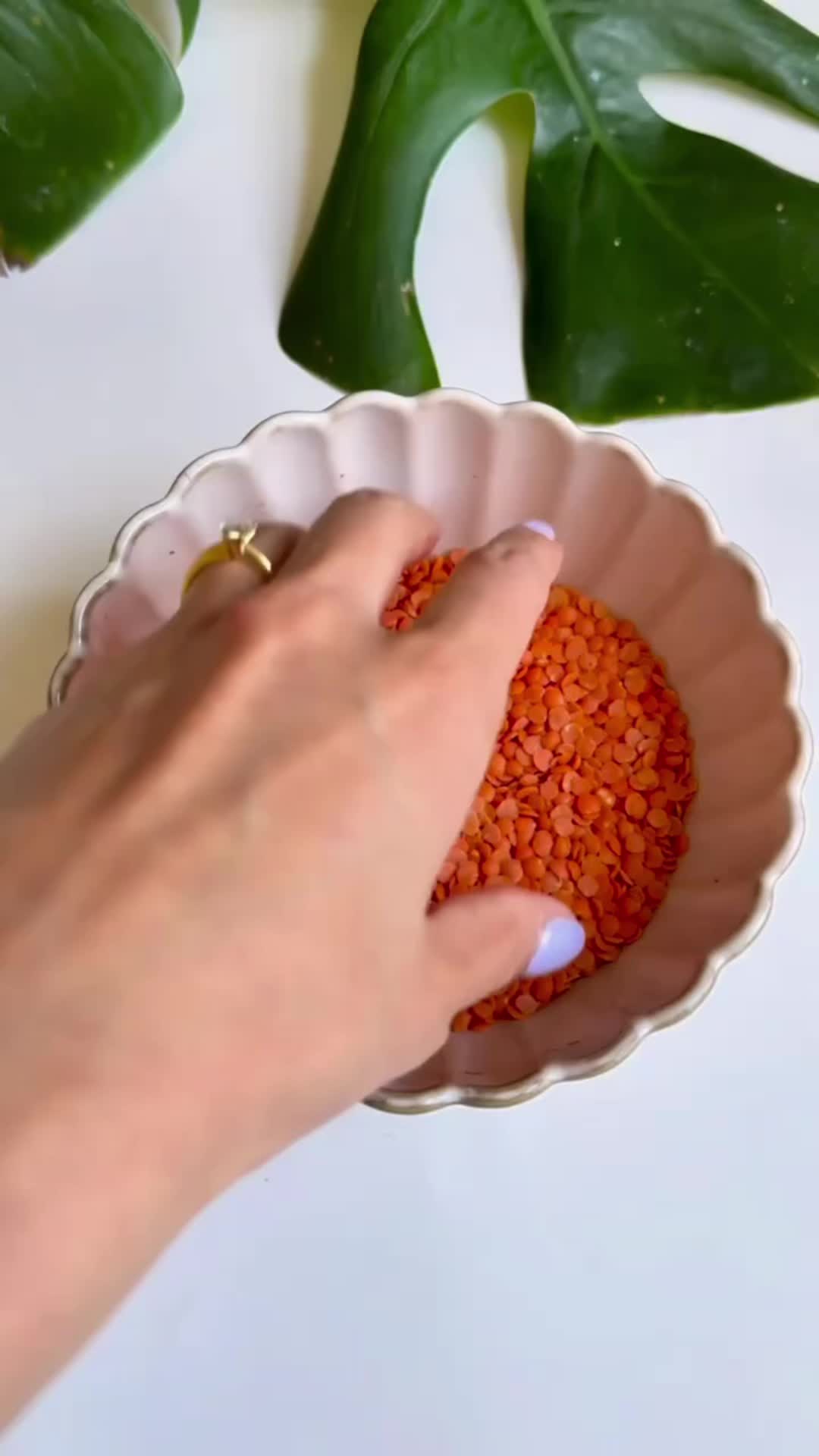 This may contain: a woman's hand is holding a red object in a bowl