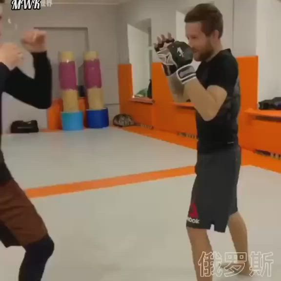 This may contain: two men are practicing boxing in an indoor gym area, one is wearing black and the other is brown