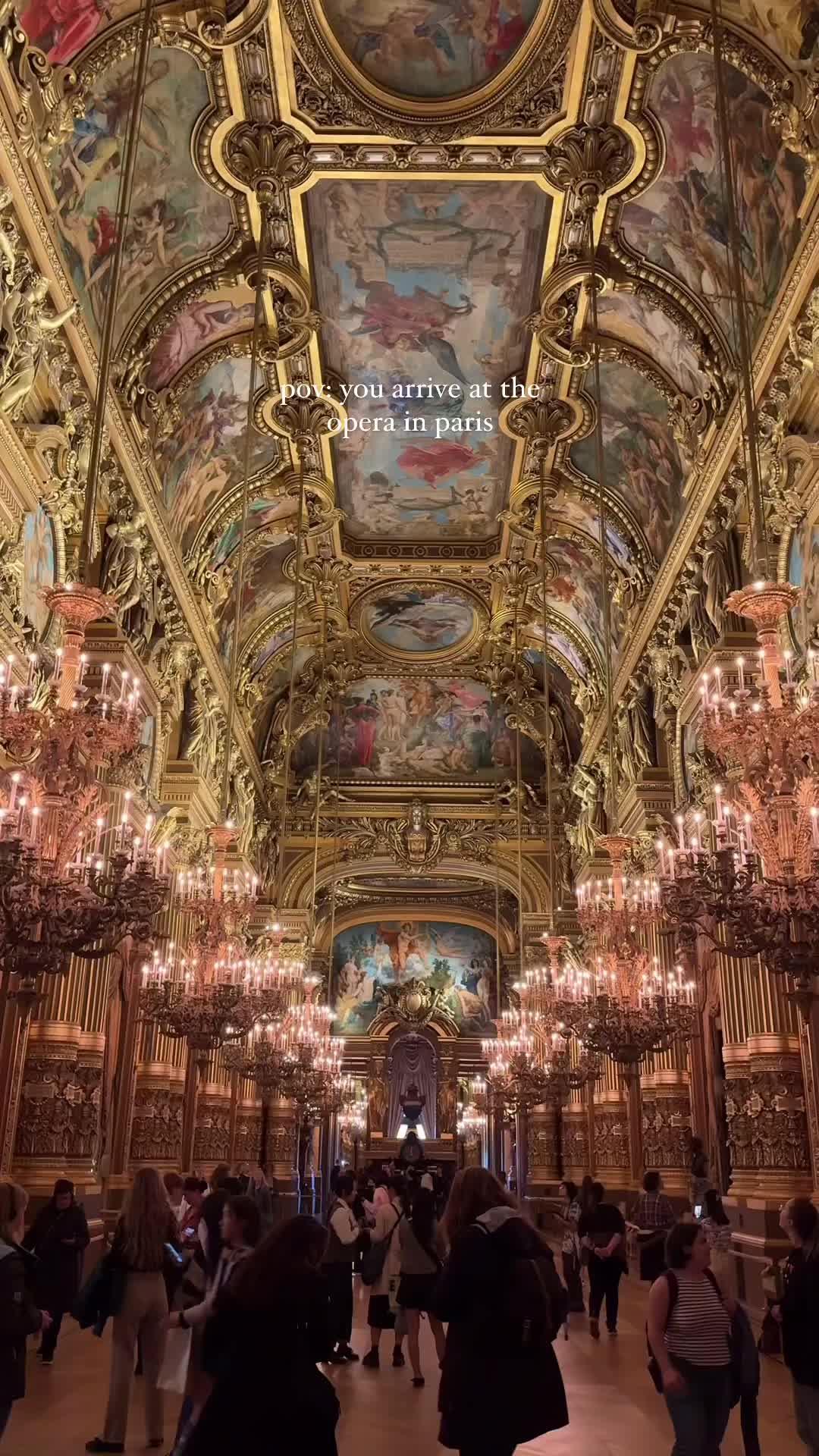 This may contain: people are walking around in an ornate building with chandeliers and paintings on the ceiling