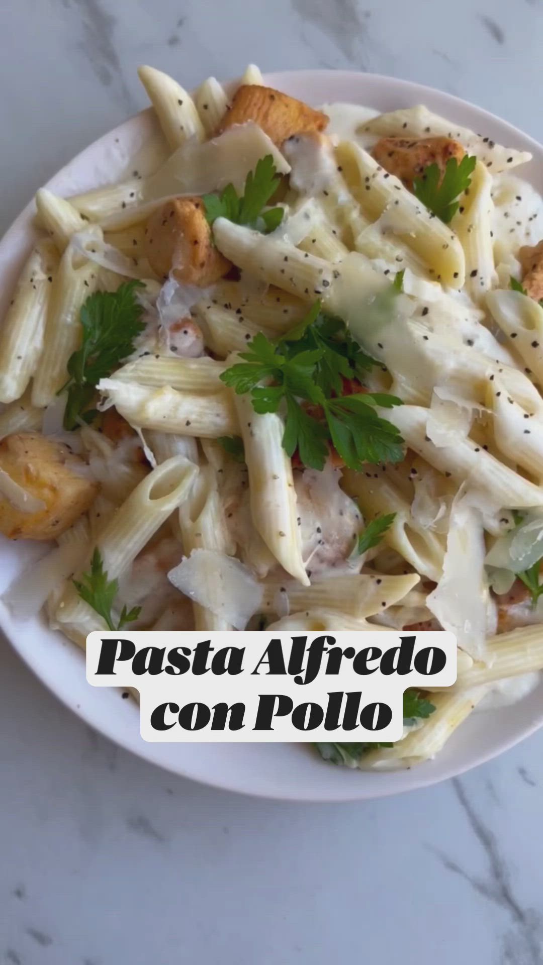 This may contain: pasta alfredo con pollo on a white plate