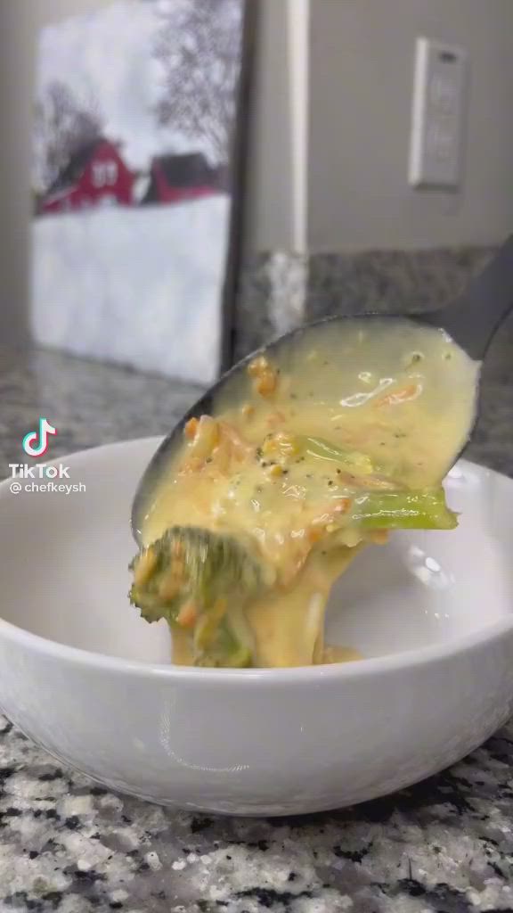 This may contain: a person in black gloves is dipping broccoli into a white bowl with bread