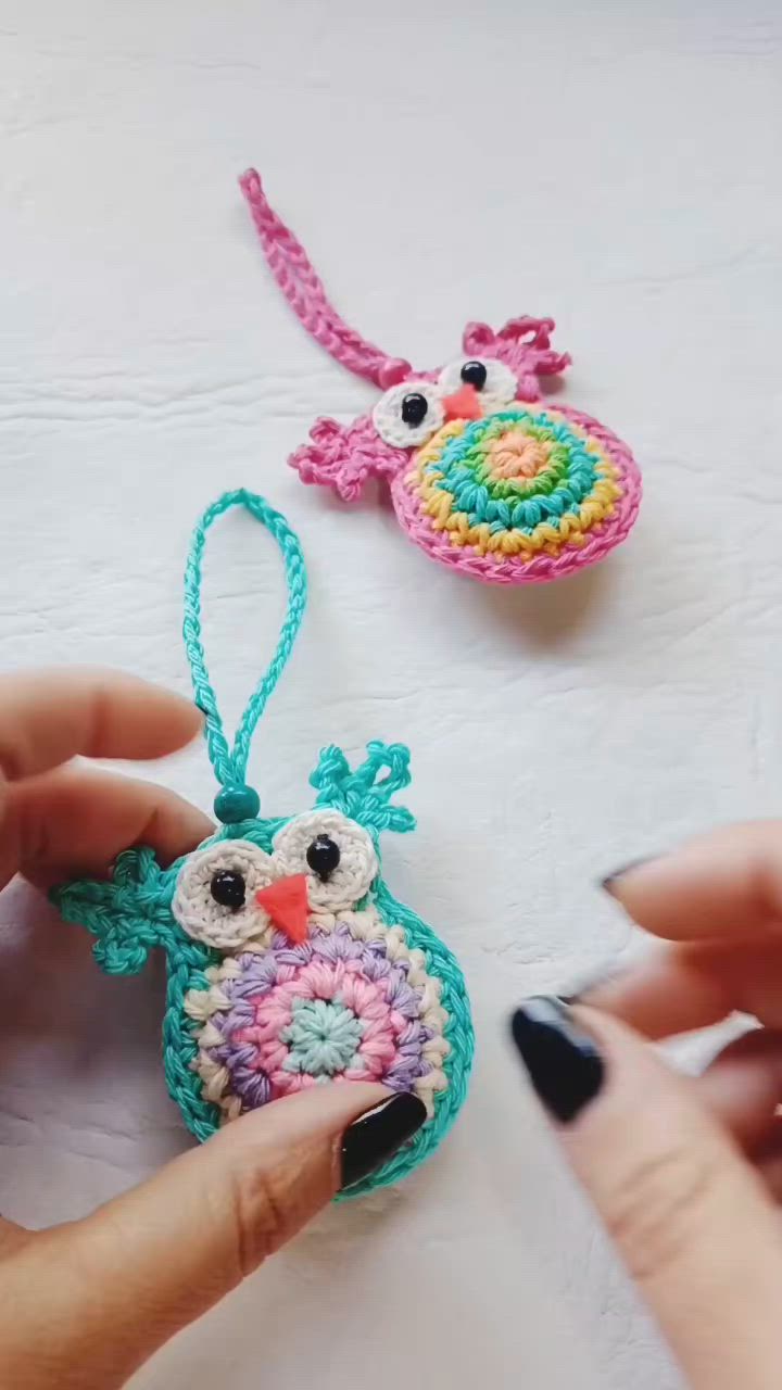 This may contain: crocheted owl ornament being held by woman's hand on white surface