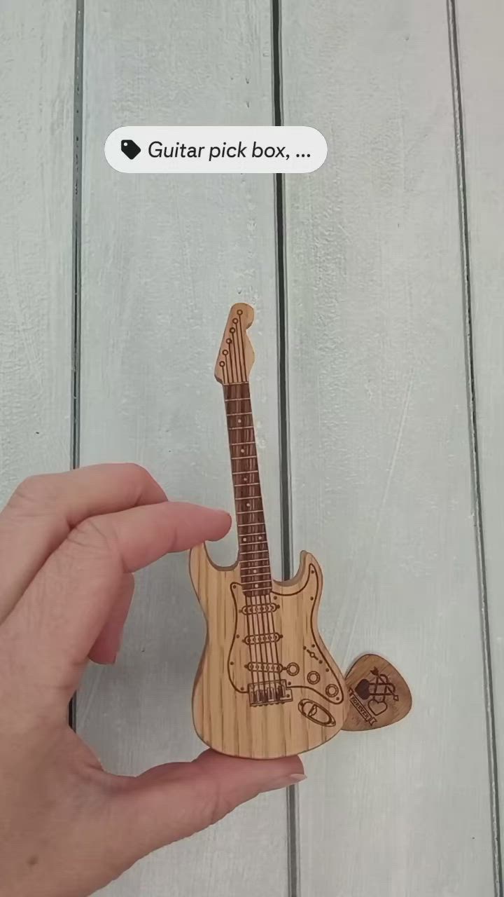 This may contain: a hand holding a wooden guitar shaped like a skull