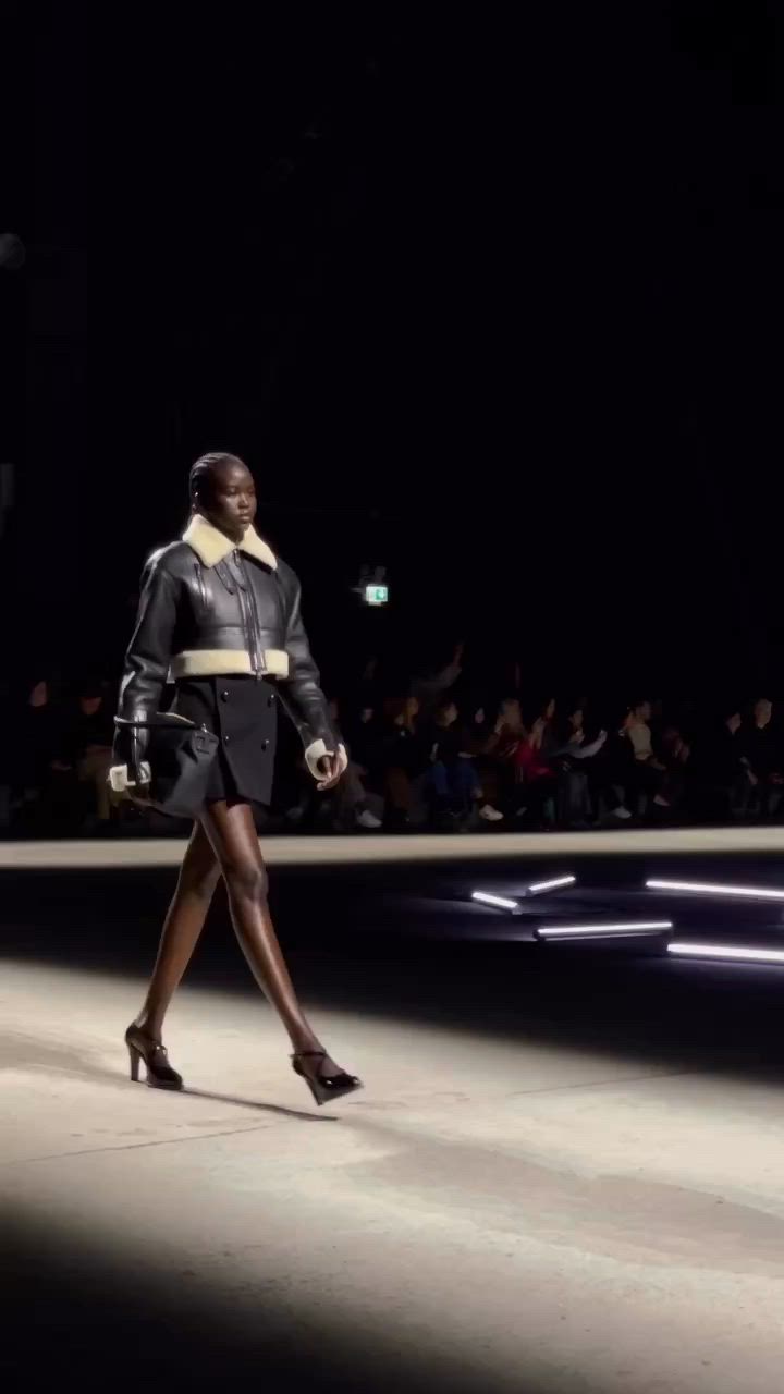 This may contain: a woman walking down a runway at night