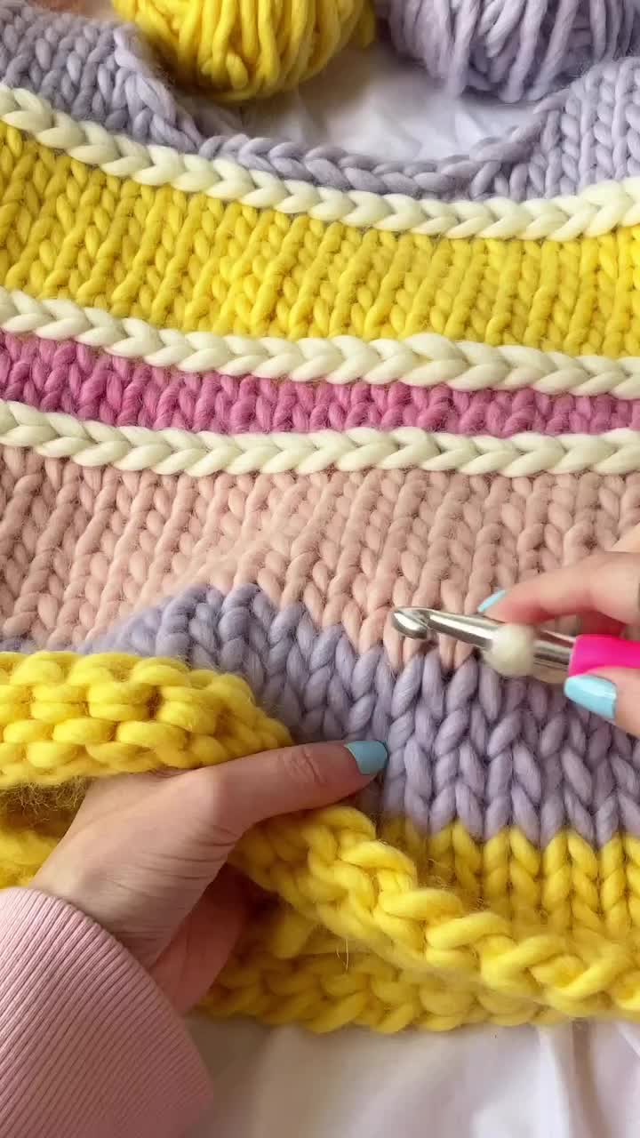 This may contain: a woman is crocheting the ends of a blanket with scissors and knitting needles