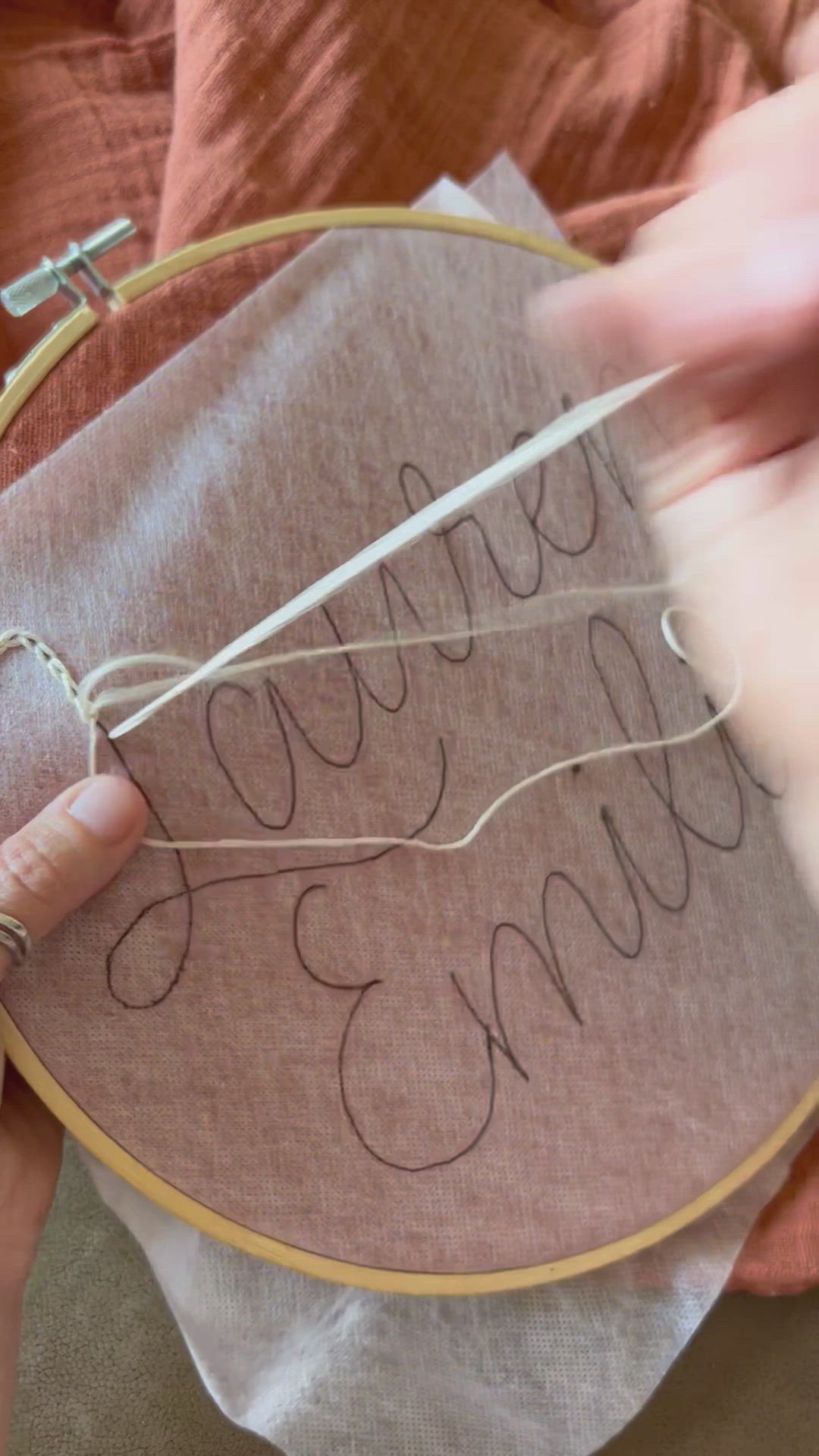 This may contain: someone is stitching the word smile on a piece of fabric in front of a cross - stitch hoop