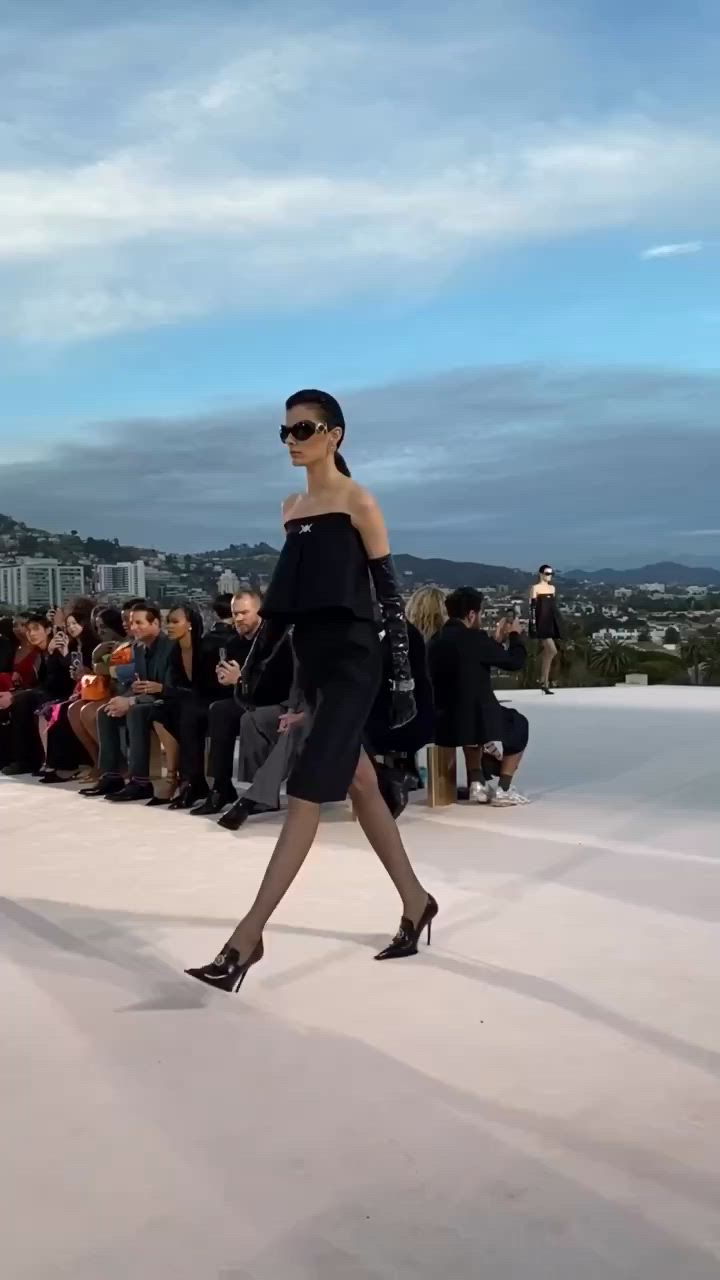 This may contain: a woman in a black and white dress is dancing on the runway with people watching