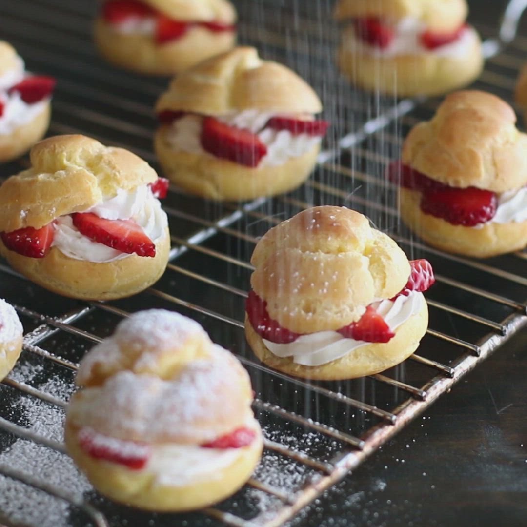 This may contain: three pastries with strawberries and powdered sugar are on a white platter