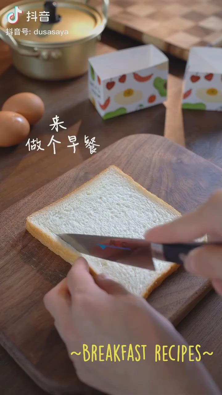 This may contain: a person cutting bread with a knife on a wooden table next to eggs and an egg carton