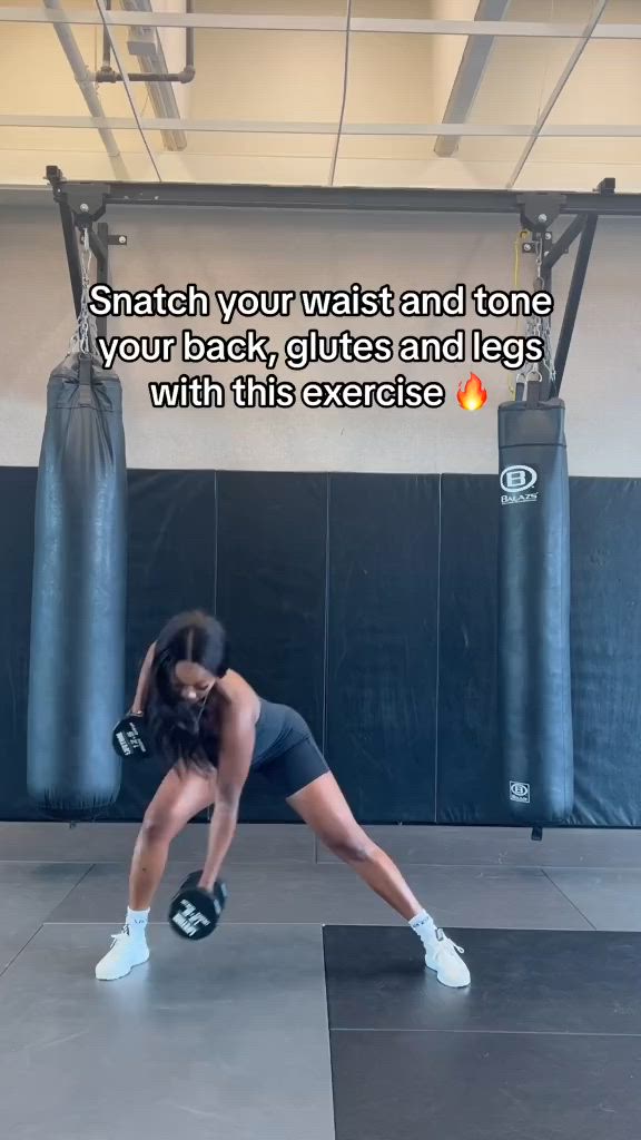 This may contain: a woman squatting on a mat in a gym with boxing gloves around her neck