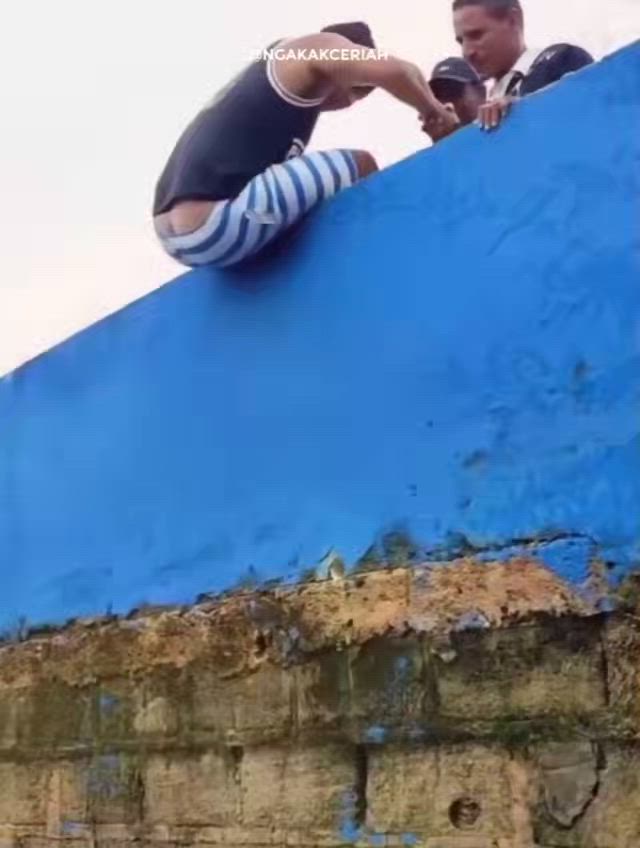 This may contain: a man is standing on the edge of a blue wall
