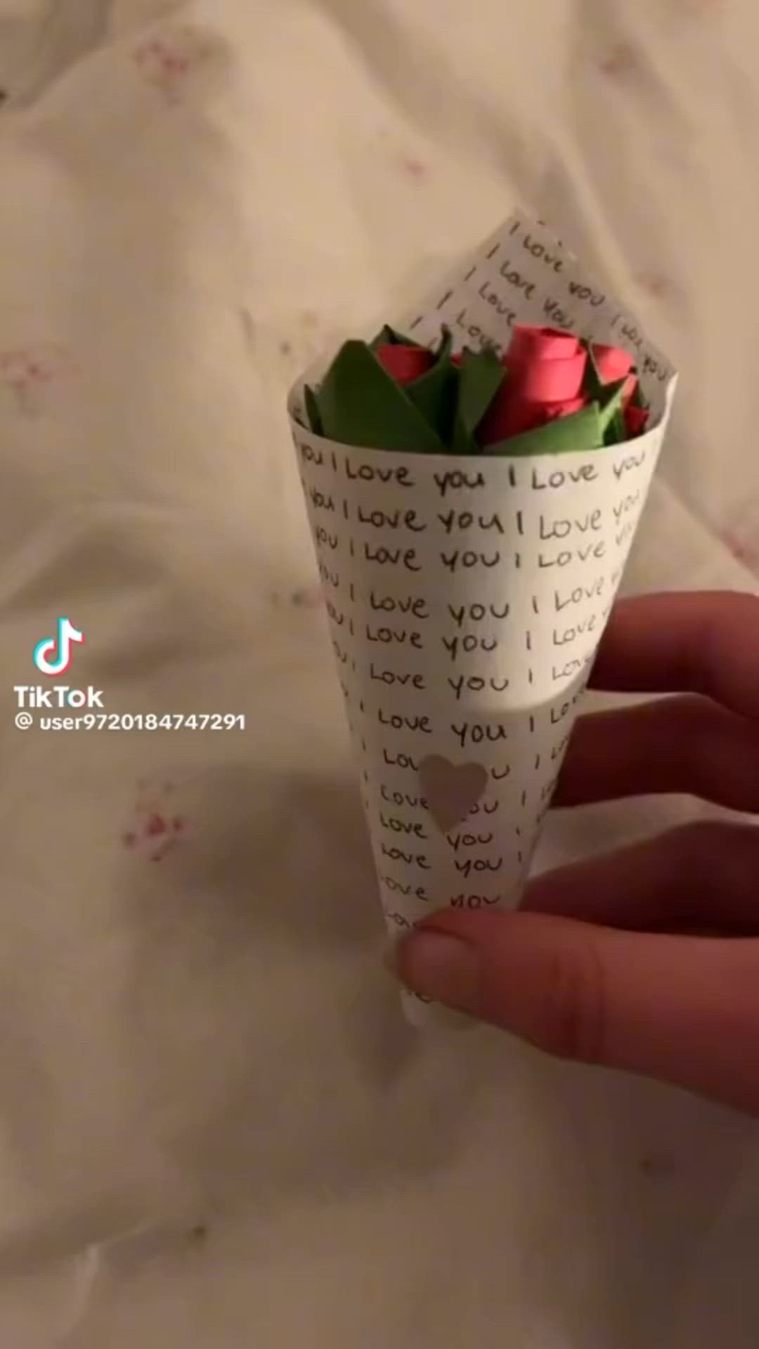 This may contain: a hand holding a paper cup with roses in it and the words i love you written on it