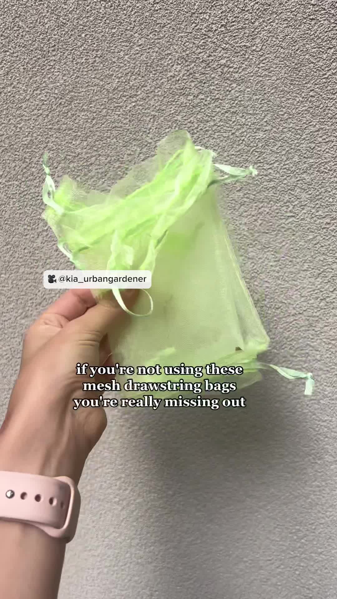 This may contain: someone is holding up a green bag with some plants in it and the words, if you're not using these mesh wrapping bags, you're really missing out