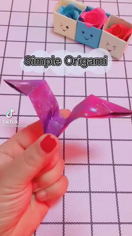 This may contain: someone is making an origami bird out of colored paper and some sort of scissors