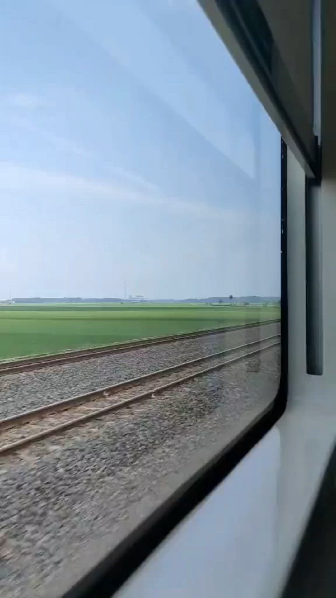 This may contain: the view from inside a train window looking out at an open field and railroad tracks